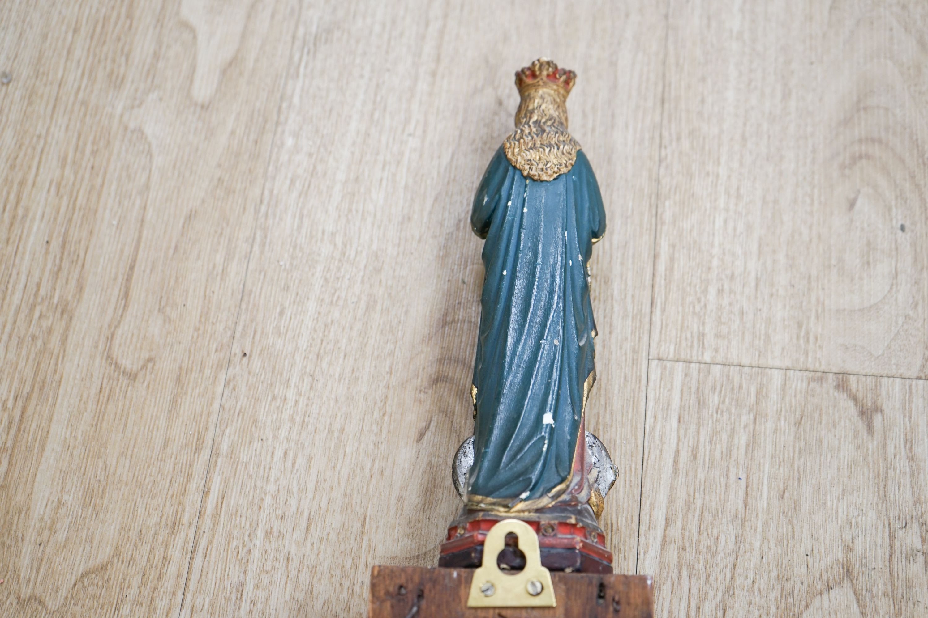 An early hand bell and a religious figure on an oak pilaster 65cm